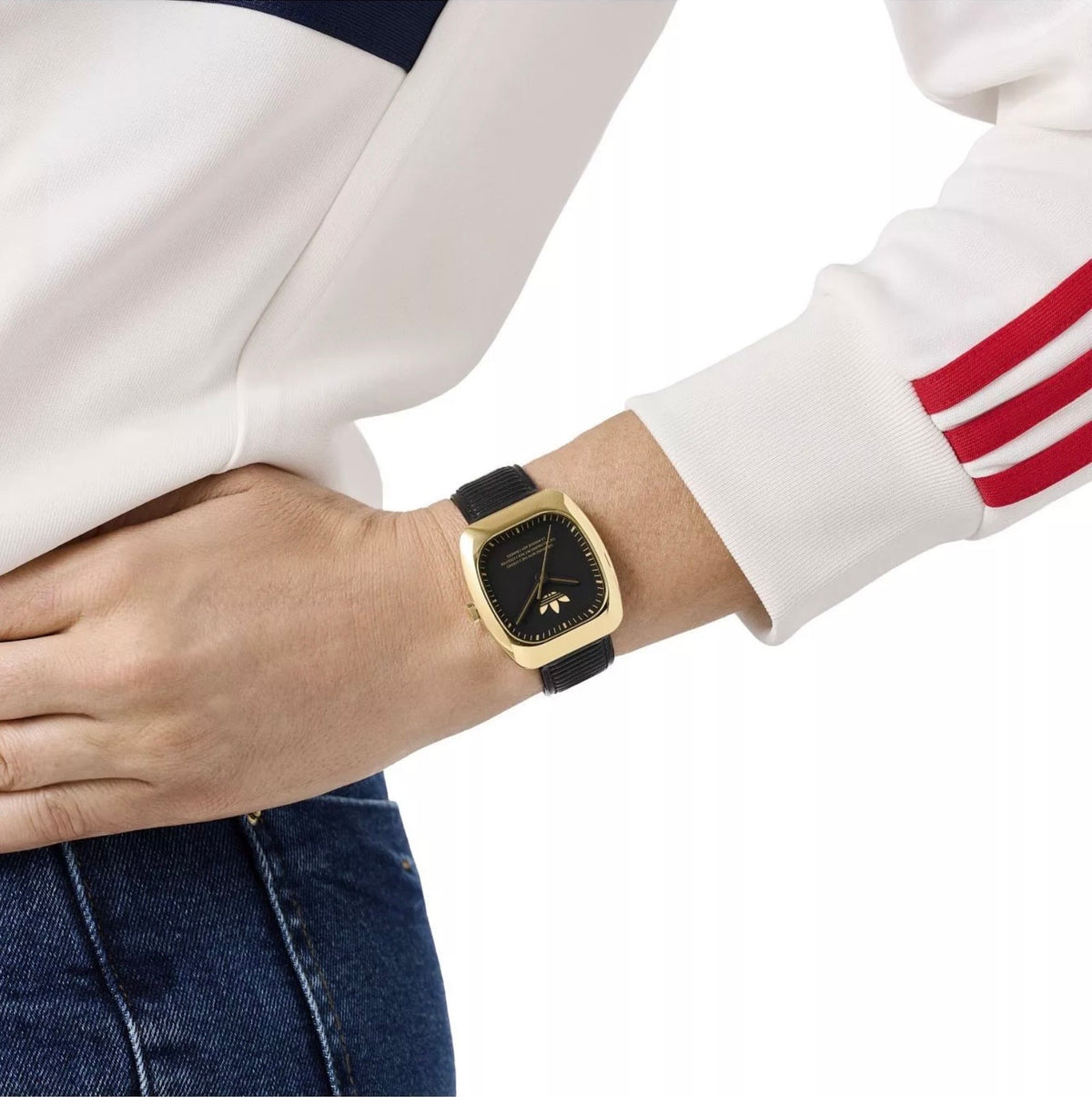 Adidas AOSY24528 watch worn on a wrist beside a white sleeve with red stripes.