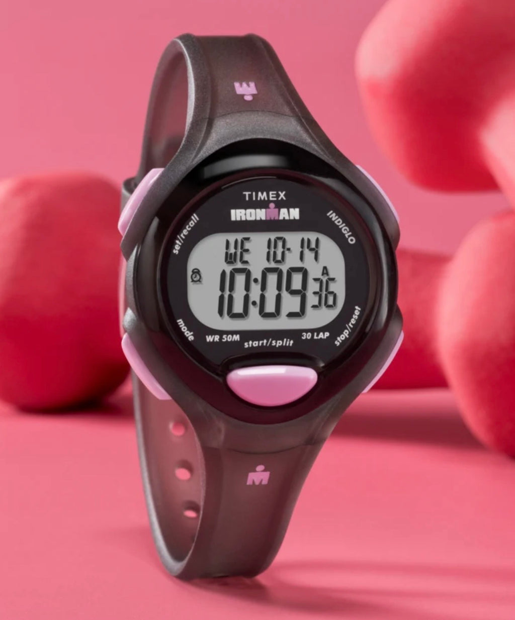 Timex TW5M65700 digital watch standing against a pink background.